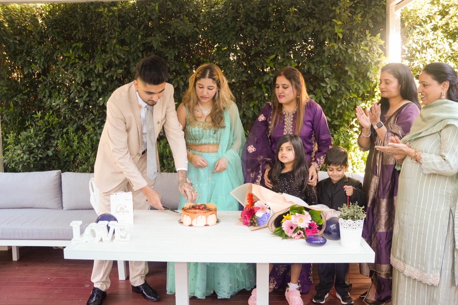 Bhavdeep and Nancy cutting their wedding cake as family look on at their Sydney backyard wedding