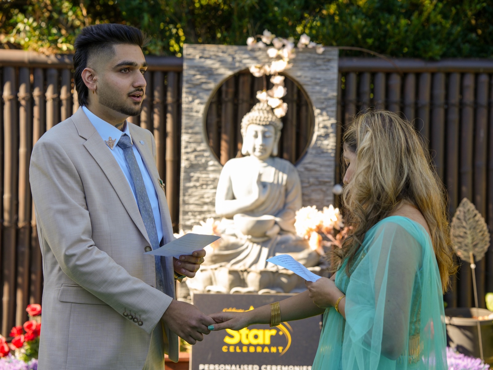 Bhavdeep reading his vows to Nancy in front of a stone Buddha at their Sydney backyard wedding