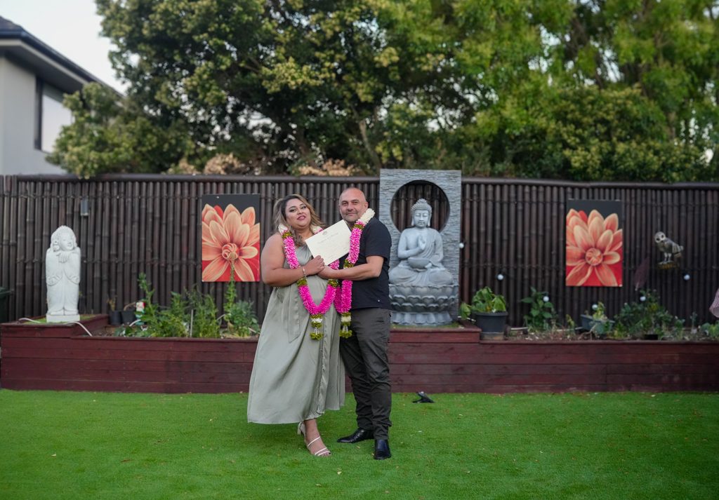 Backyard wedding ceremony in Sydney with a Fijian couple holding their marriage certificate in a garden setting