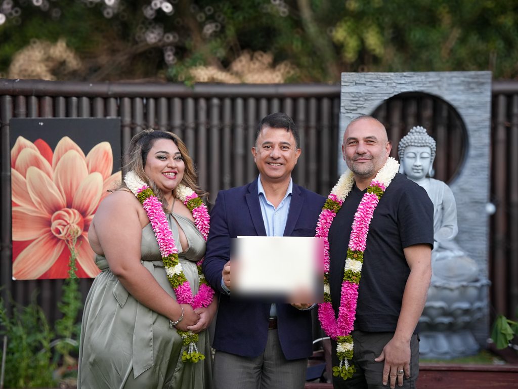 Sydney marriage celebrant Rohit Revo presenting the certificate of marriage to a garlanded couple