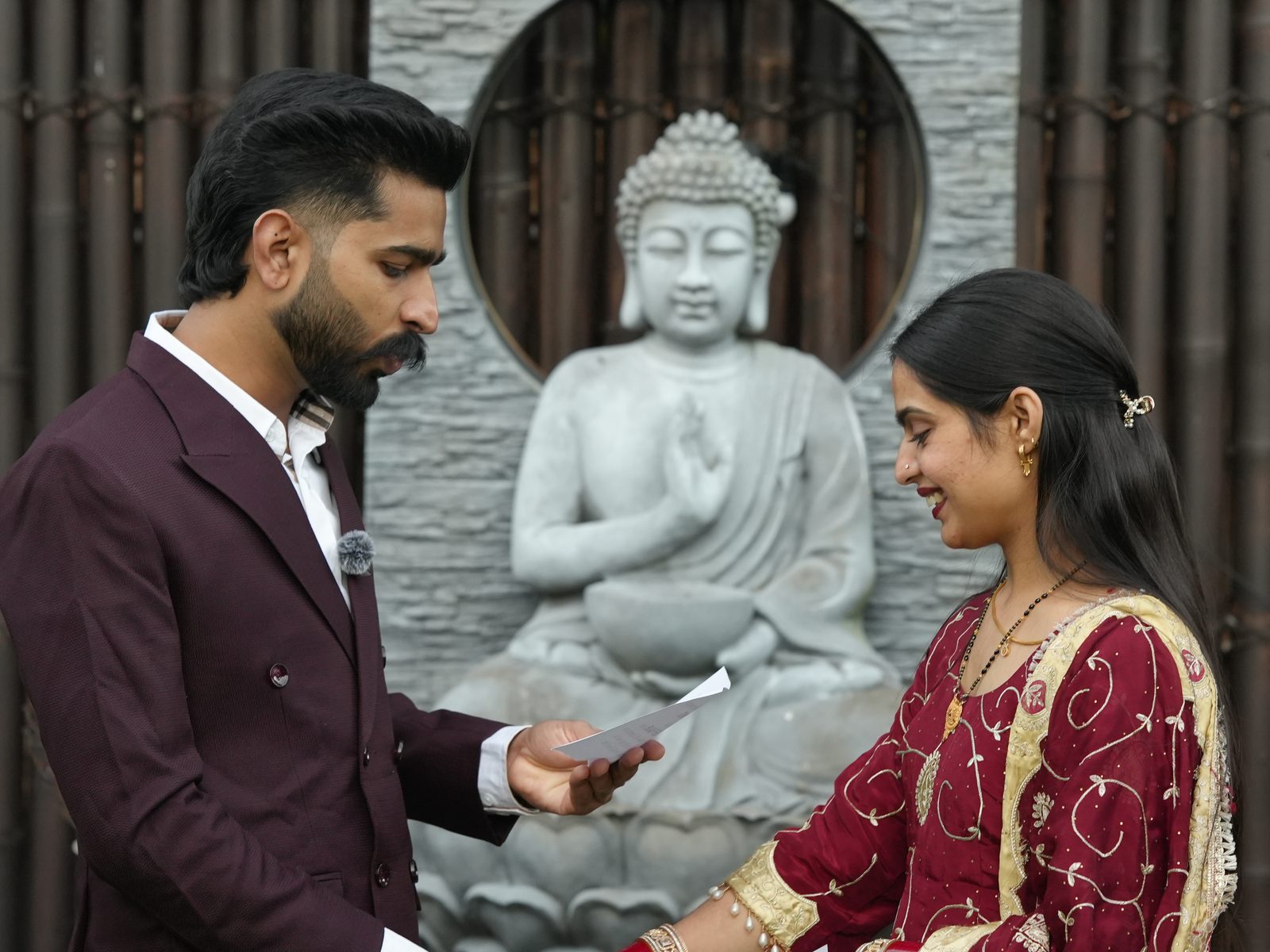 A couple reading their vows to each other in the Bella Vista garden, Buddha statue behind them