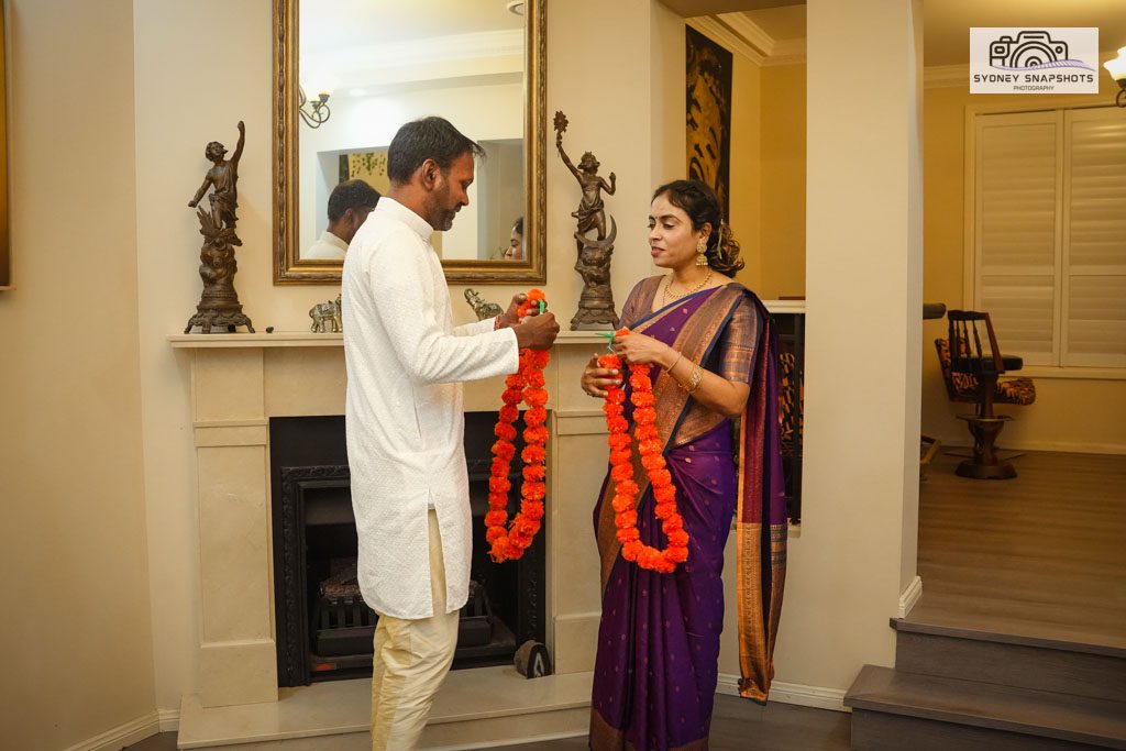 A couple exchanging garlands at an intimate Indian wedding ceremony at home in Sydney