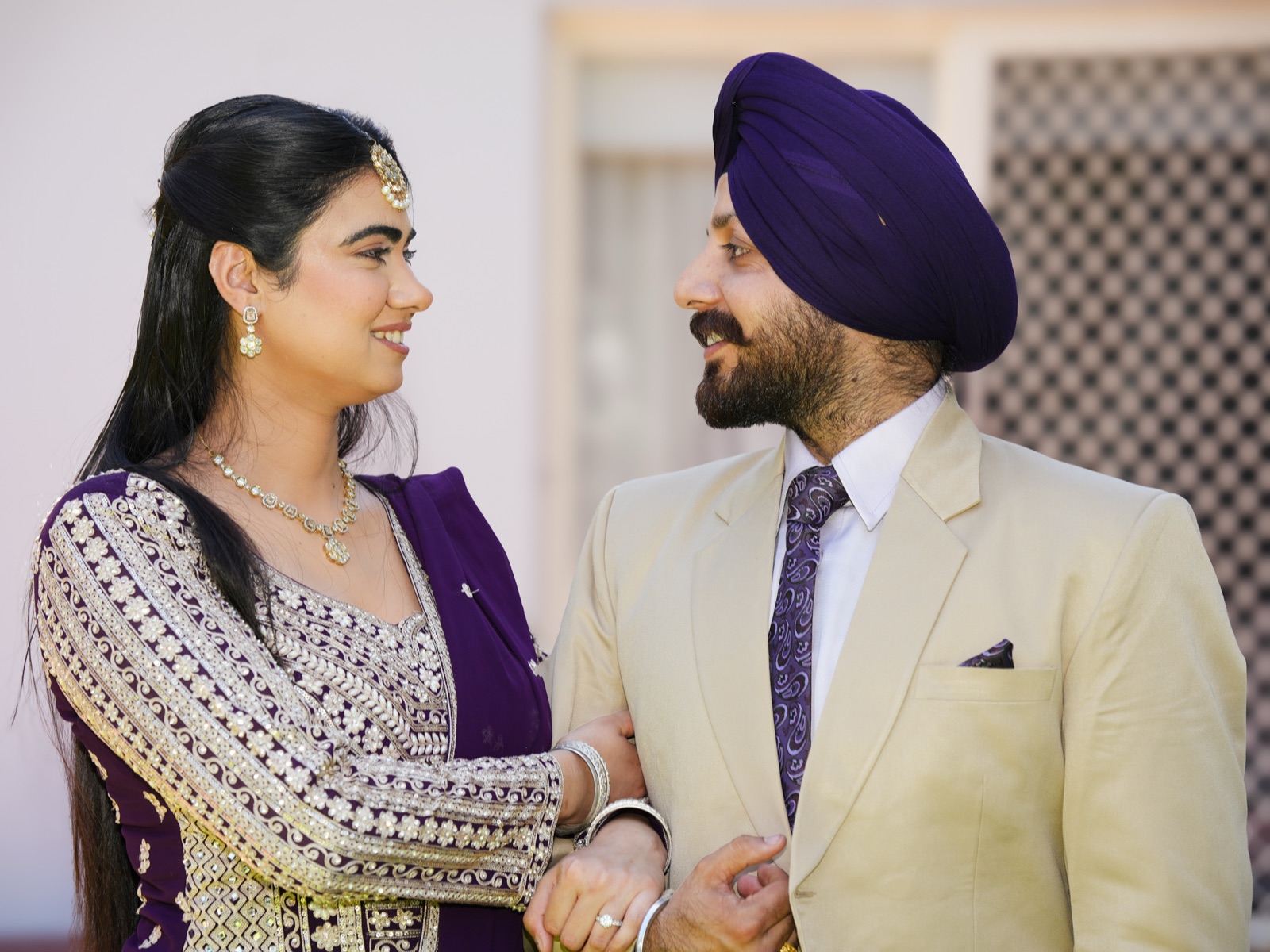 Kanwarpal and Jashandeep looking at each other and laughing, arm in arm, after their garden wedding in Sydney