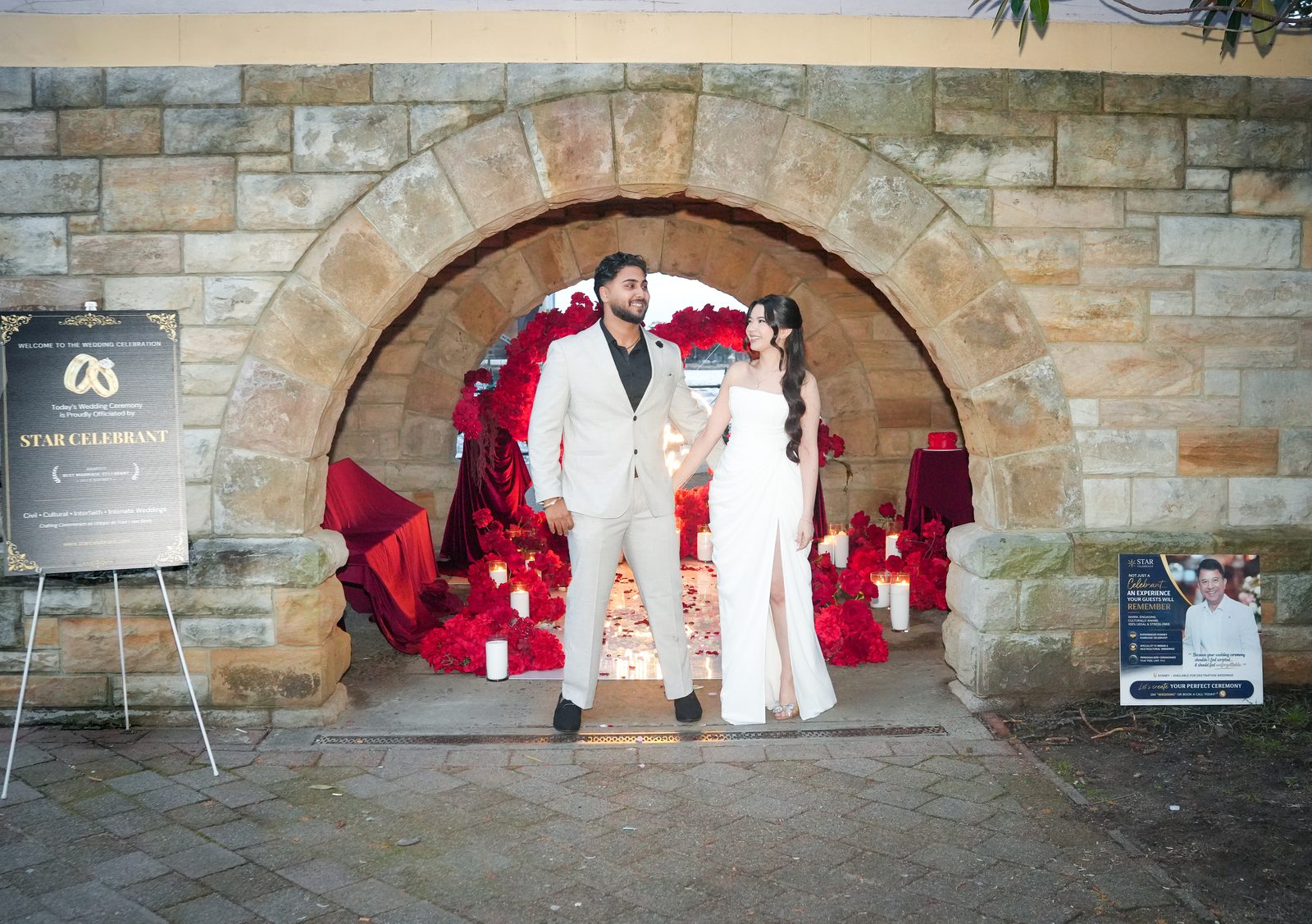 Candlelit wedding ceremony under a sandstone arch at Milsons Point, styled with red roses, officiated by Star Celebrant