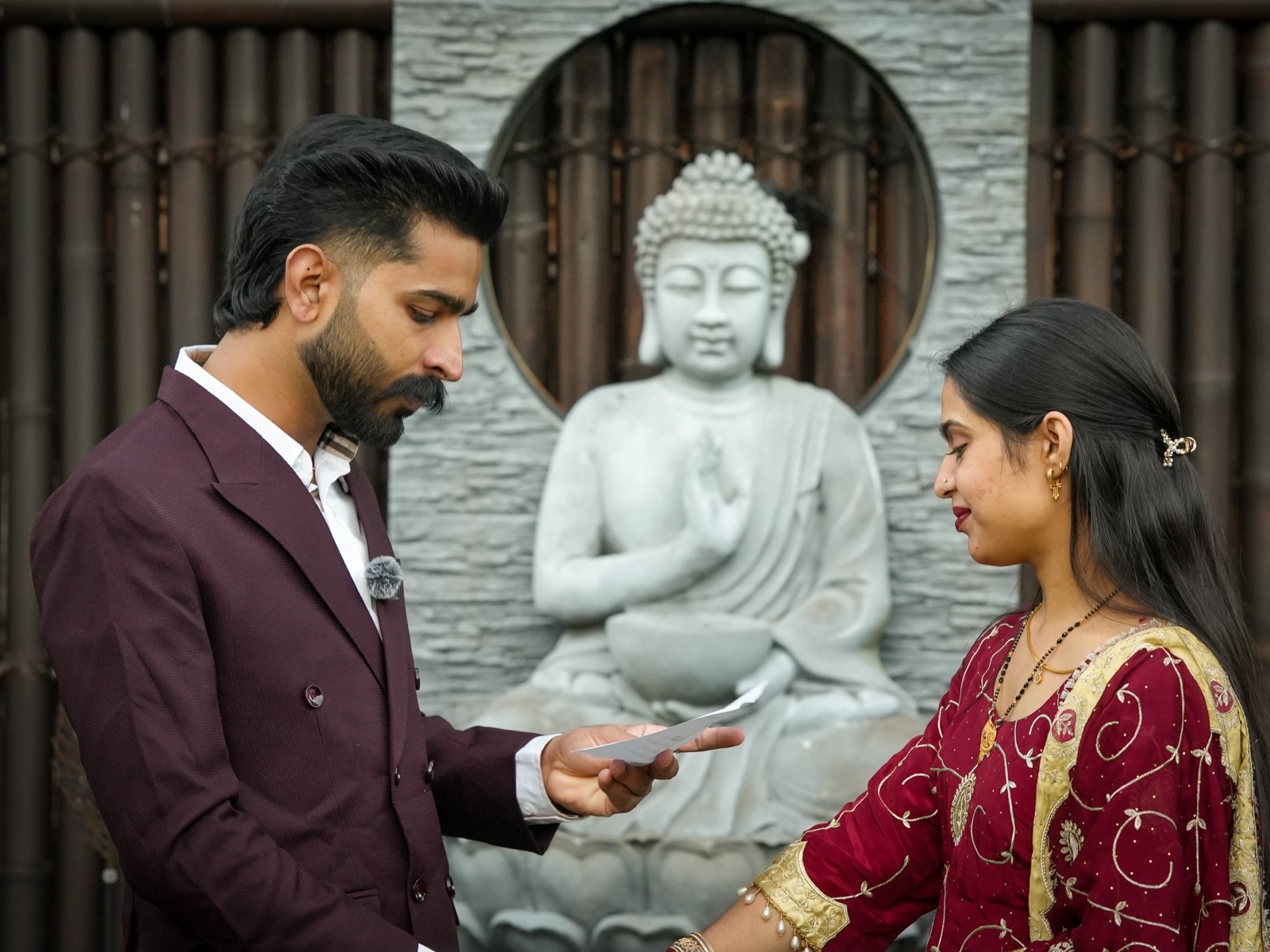 Prince and Sagandeep exchanging rings in front of a stone Buddha at their backyard elopement in Sydney