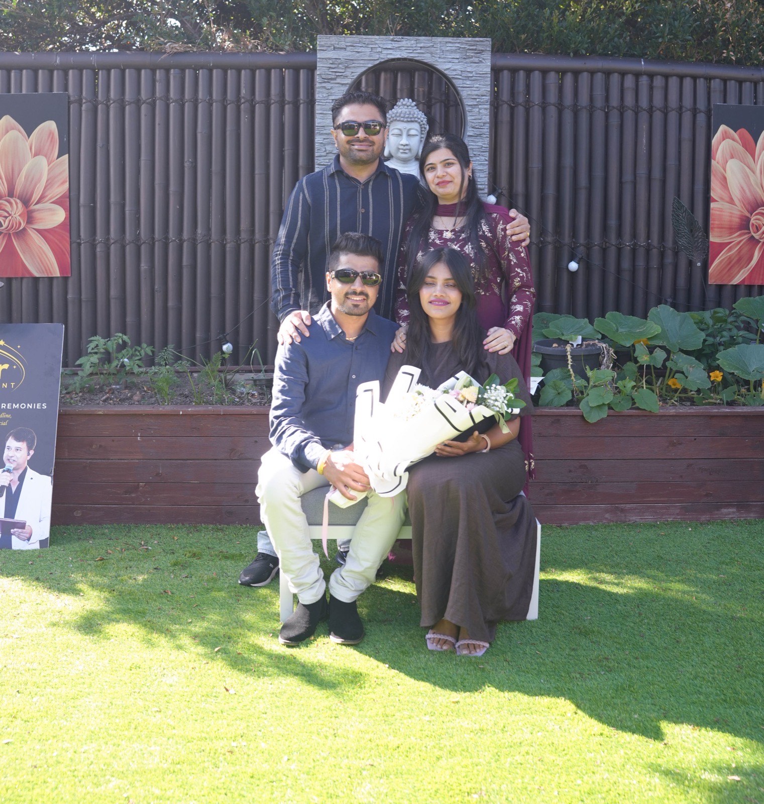 Sahil and Radhika seated together with family in front of the garden Buddha at their Sydney wedding