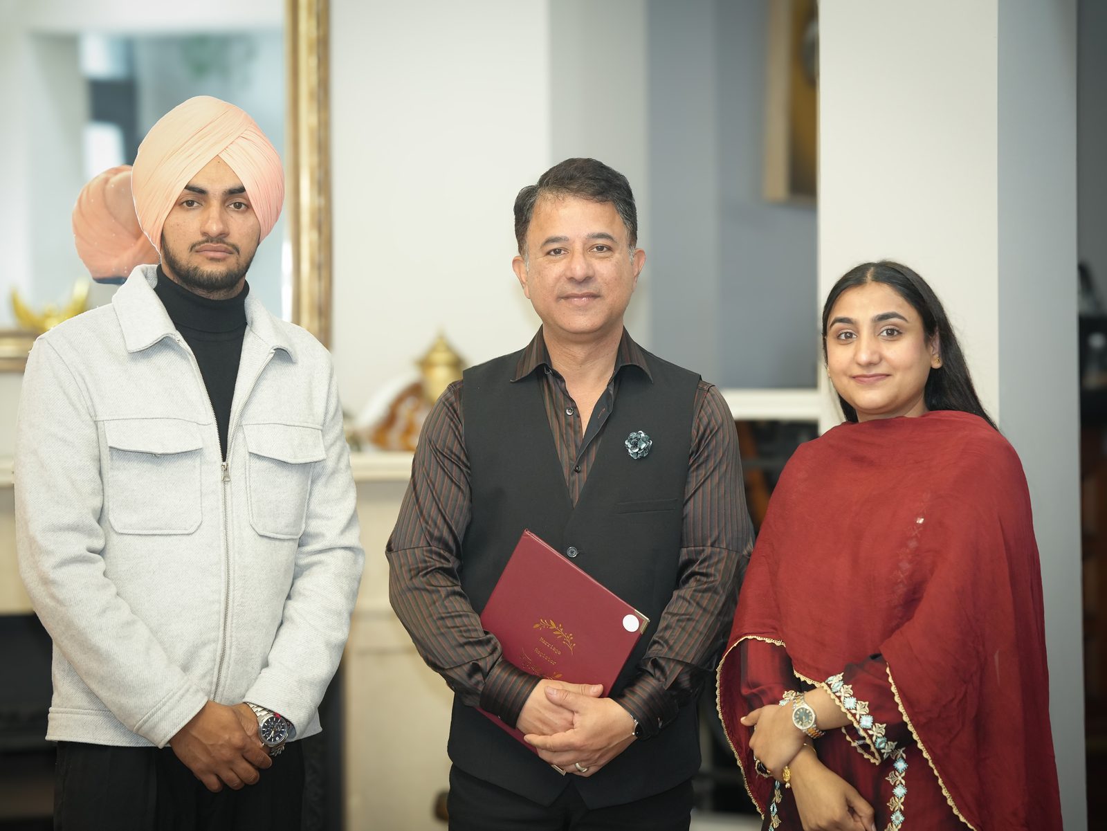 Inder and Anchaldeep standing either side of their celebrant, who holds their marriage certificate, at their Sikh court marriage in Sydney