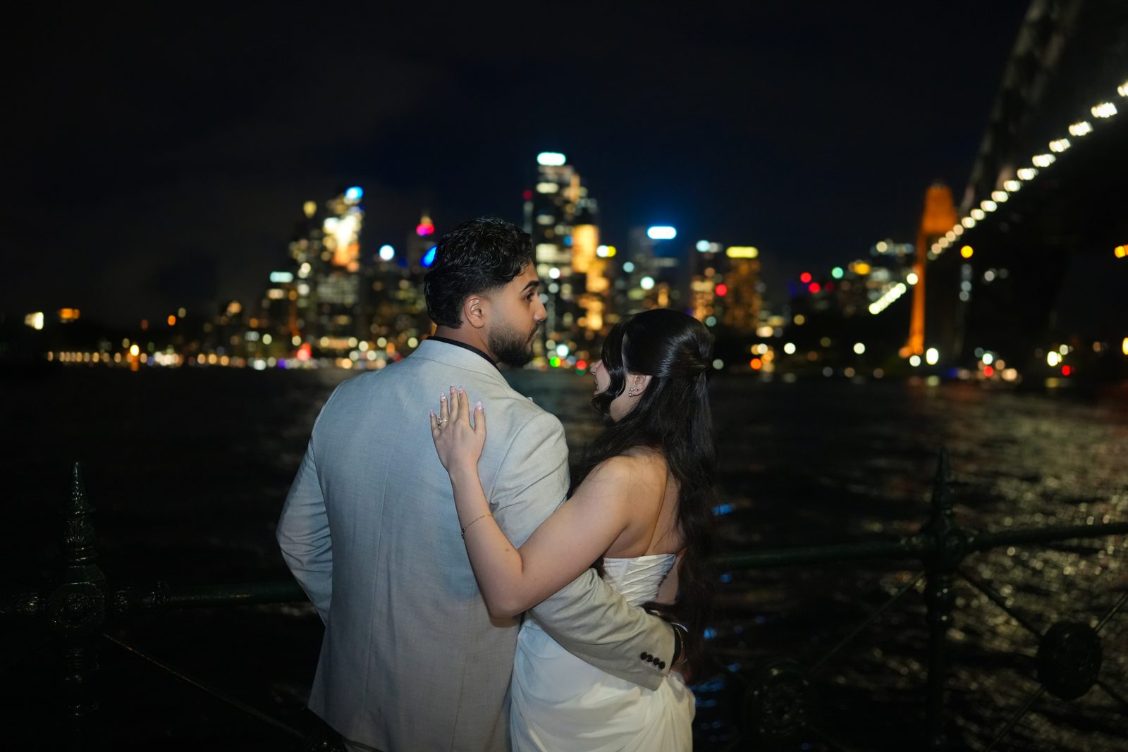 Bride and groom embracing as they look out over the Sydney city skyline at night