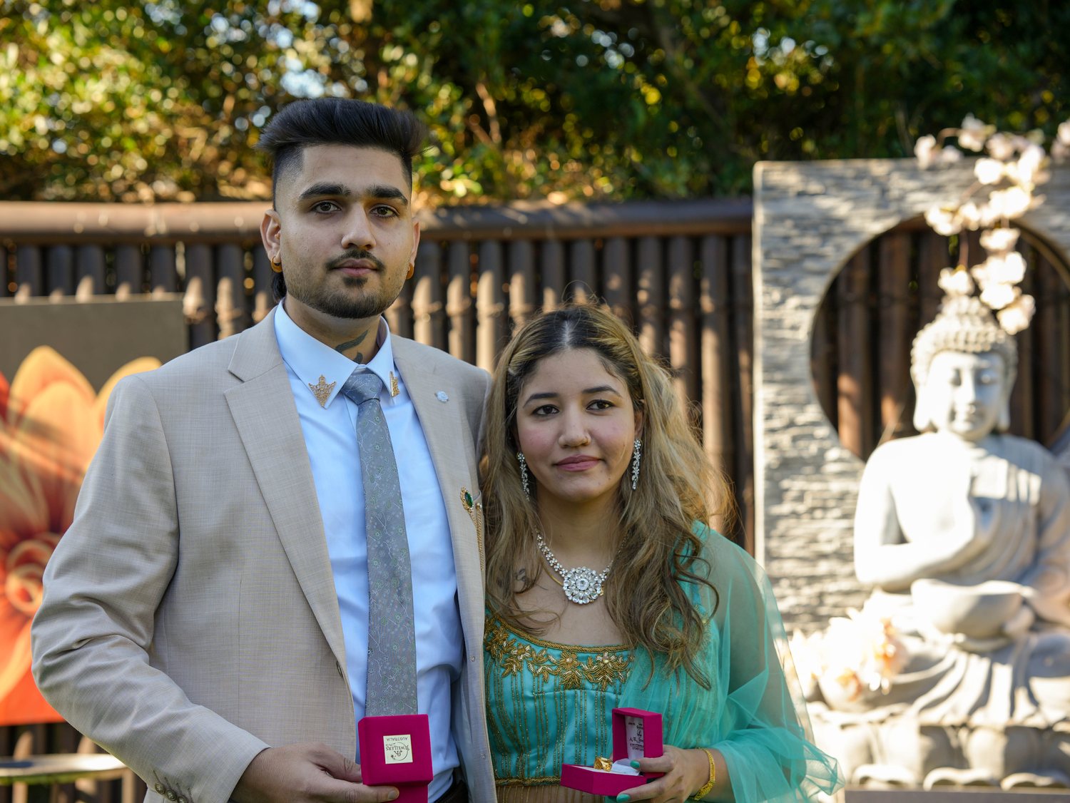 A couple holding their wedding ring boxes in a Sydney garden at golden hour