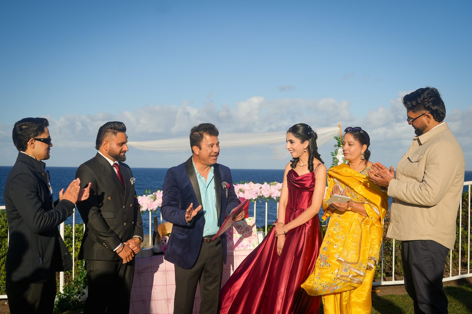 Guests applauding as Rohit Revo conducts Lovepreet and Gurpinder's wedding ceremony on the headland at Wollongong lighthouse