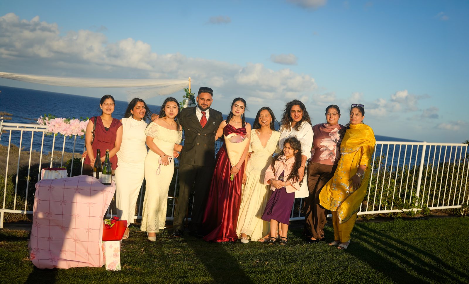 Gurpinder and Lovepreet with family and friends smiling on the lawn above the ocean at Wollongong lighthouse